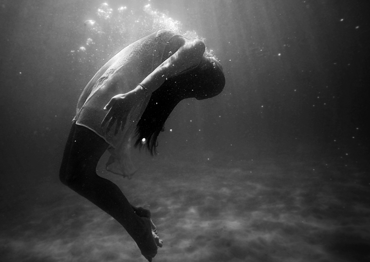 Persoon die onder water achterovergebogen naar de lichtinval beweegt
