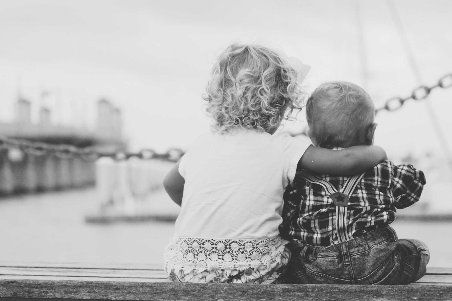 Twee jonge kinderen van achteren gezien terwijl ze aan het water zitten