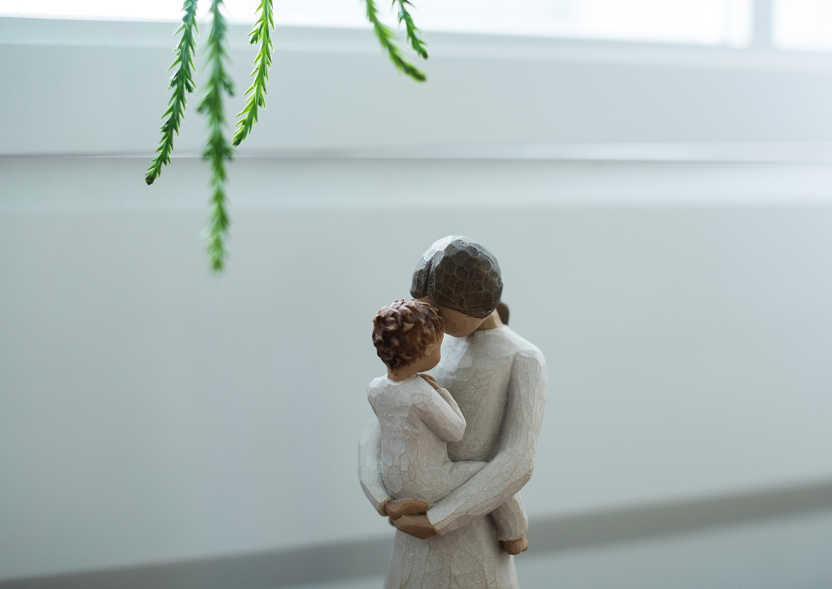 Zwangere vrouw die haar jonge kind omhelst in een lichte kamer