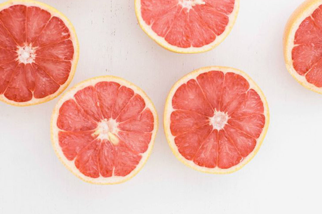 Meerdere doorgesneden grapefruits op een witte achtergrond
